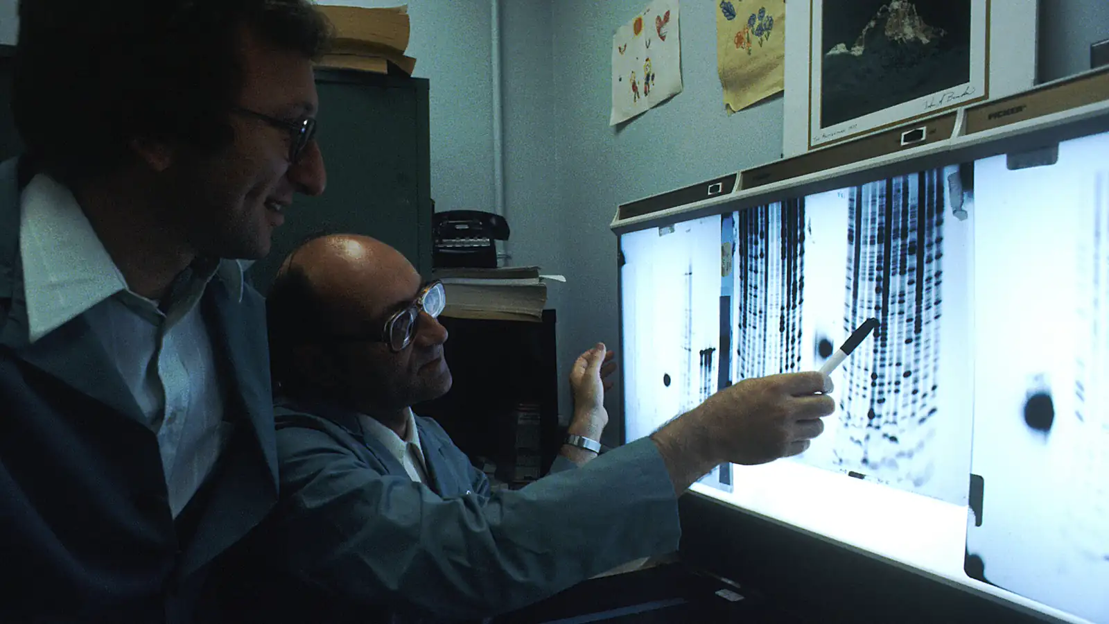 Two scientists examining illuminated DNA sequencing data in a laboratory