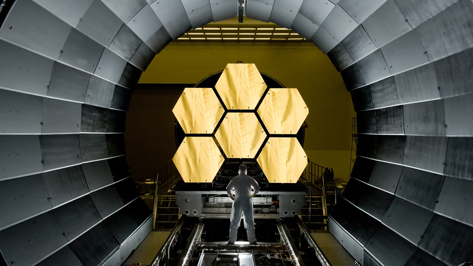 Technician inspecting the gold primary mirror of the James Webb Space Telescope