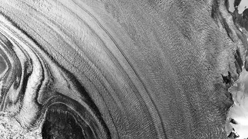 Close aerial view of curved fractures and flow lines across glacier ice