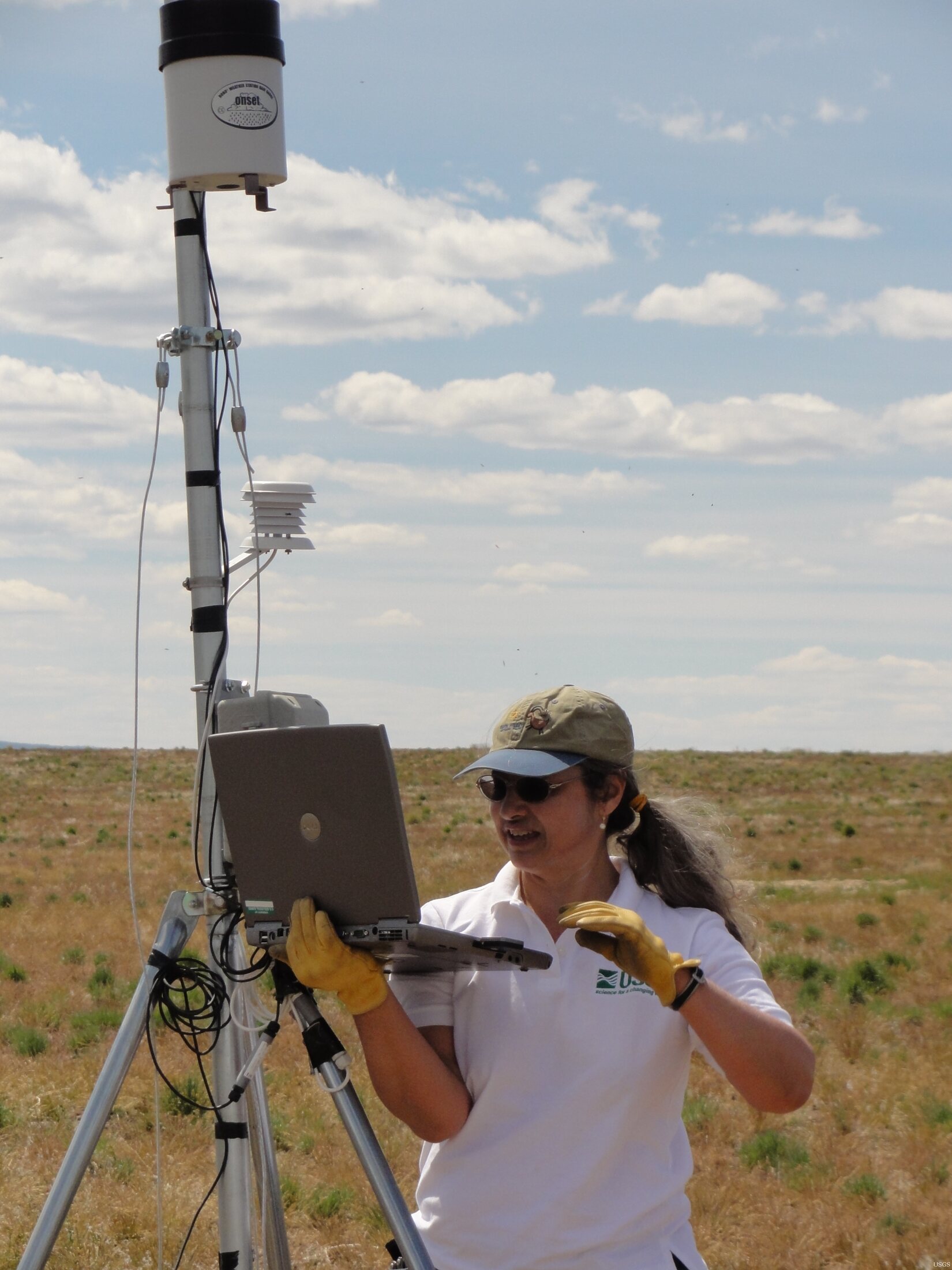 USGS scientist downloading environmental data from a field weather station