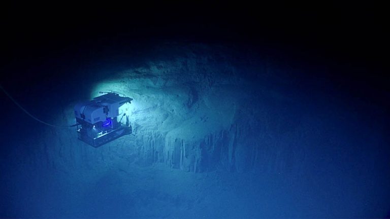 Remotely operated vehicle lights illuminating a rocky feature on the deep seafloor