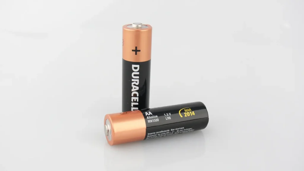Close-up photograph of a standard AA alkaline battery on a plain background