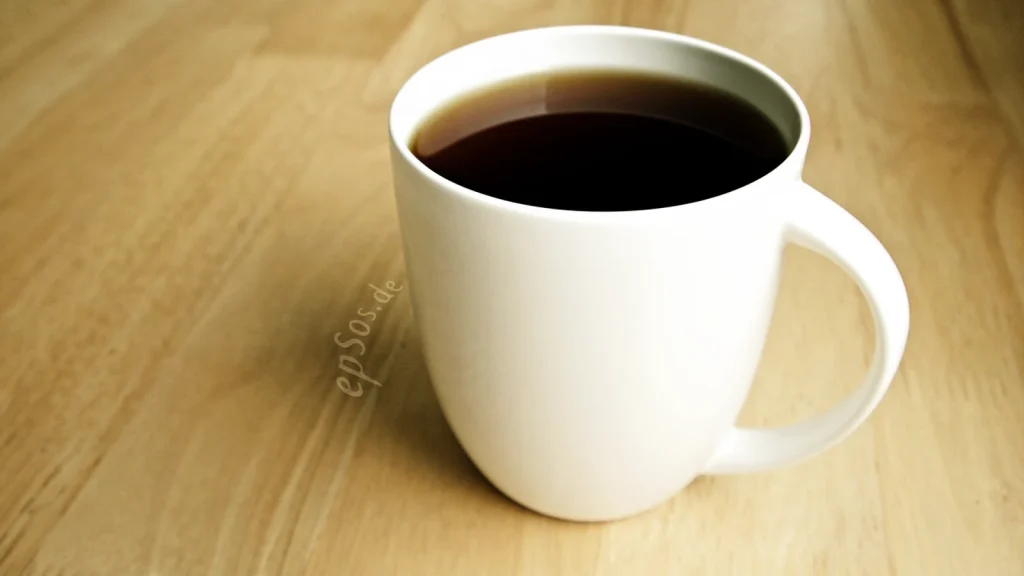 Steam rising from a hot dark drink in a white ceramic cup