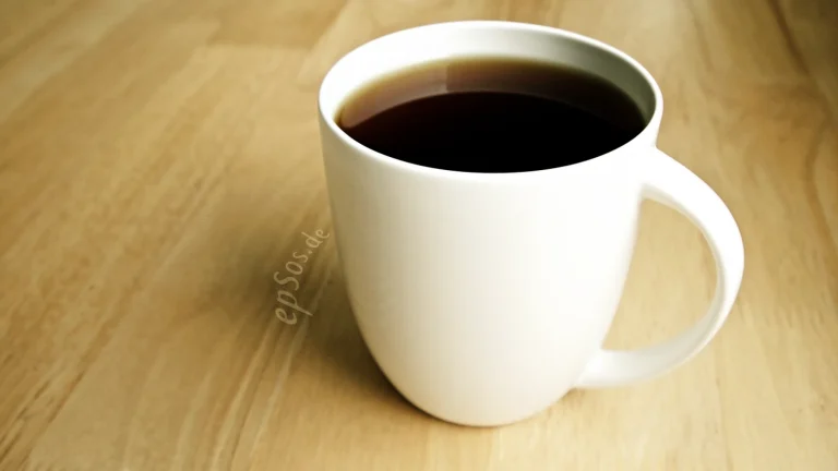 Steam rising from a hot dark drink in a white ceramic cup