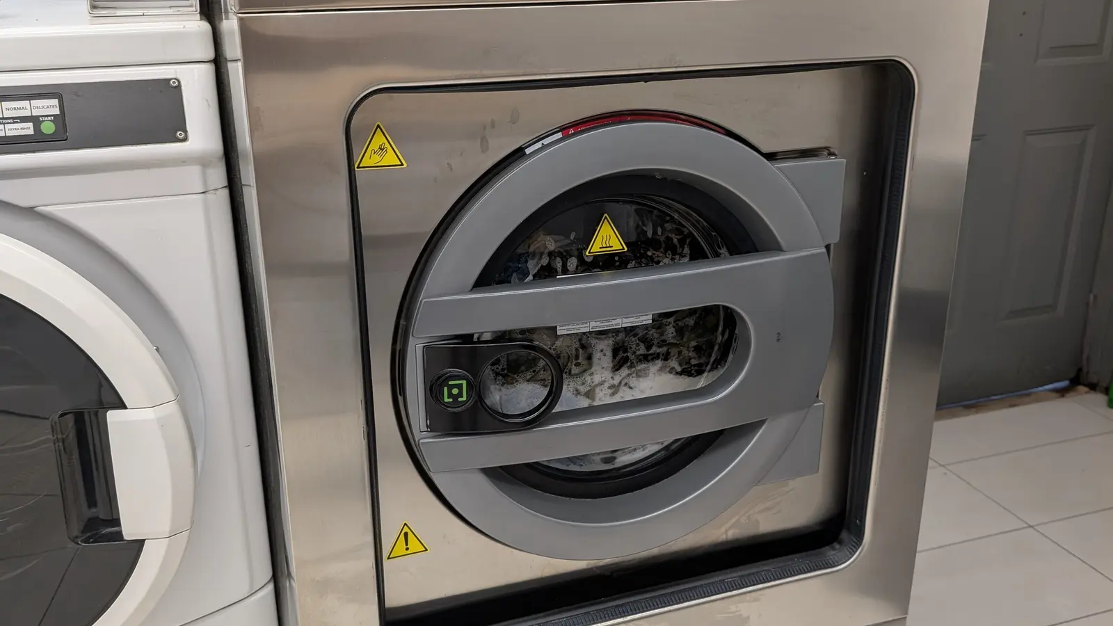 Front-loading commercial washing machine inside a Toronto laundromat