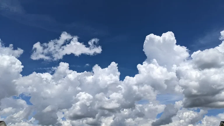 Bright white cumulus clouds rising through a deep blue summer sky