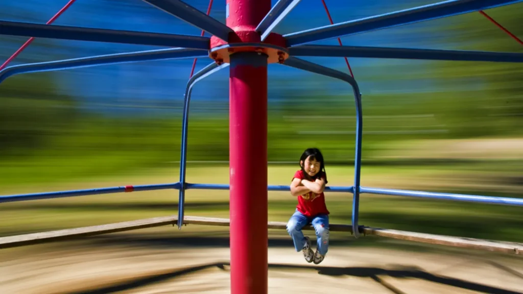 Children riding a spinning playground merry-go-round outdoors
