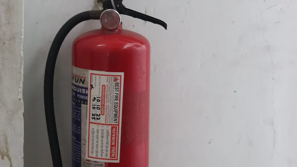 Red portable fire extinguisher mounted on an office wall
