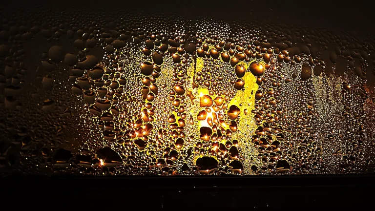 Water droplets from condensation covering a glass window at sunset