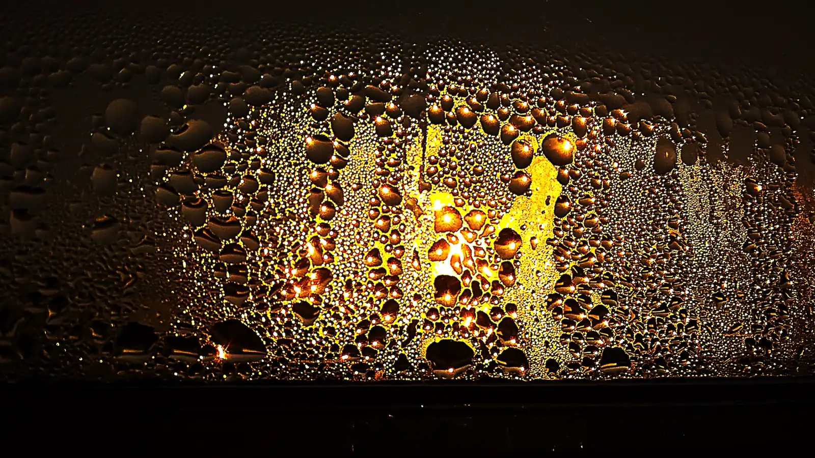Water droplets from condensation covering a glass window at sunset