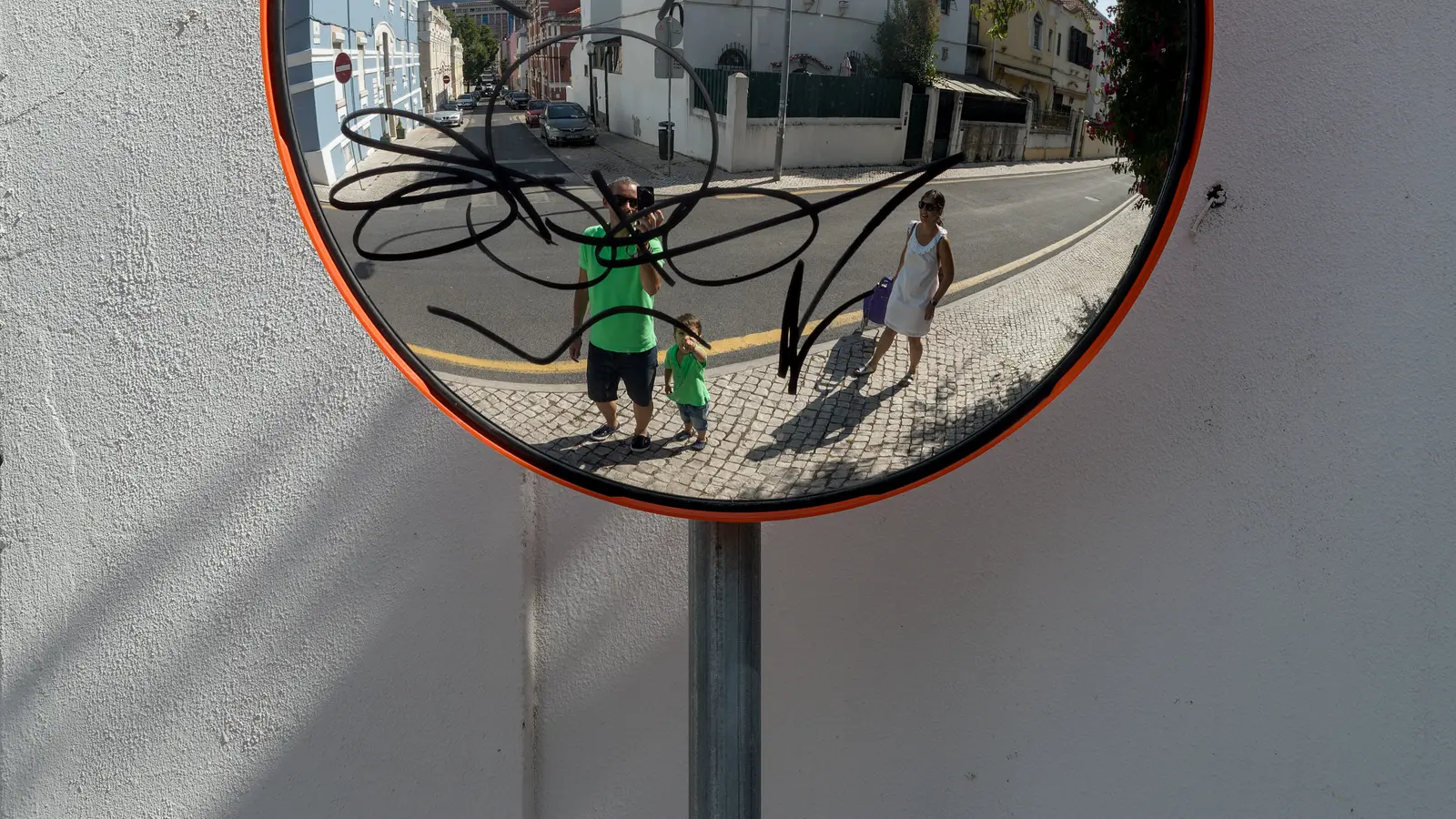 Three people reflected in a circular street mirror