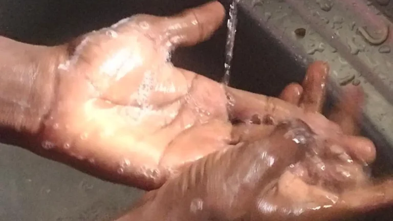 Hands covered with soap lather being washed under running water
