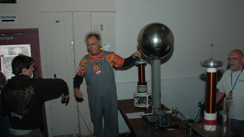 Person with hair standing outward during a Van de Graaff generator demonstration